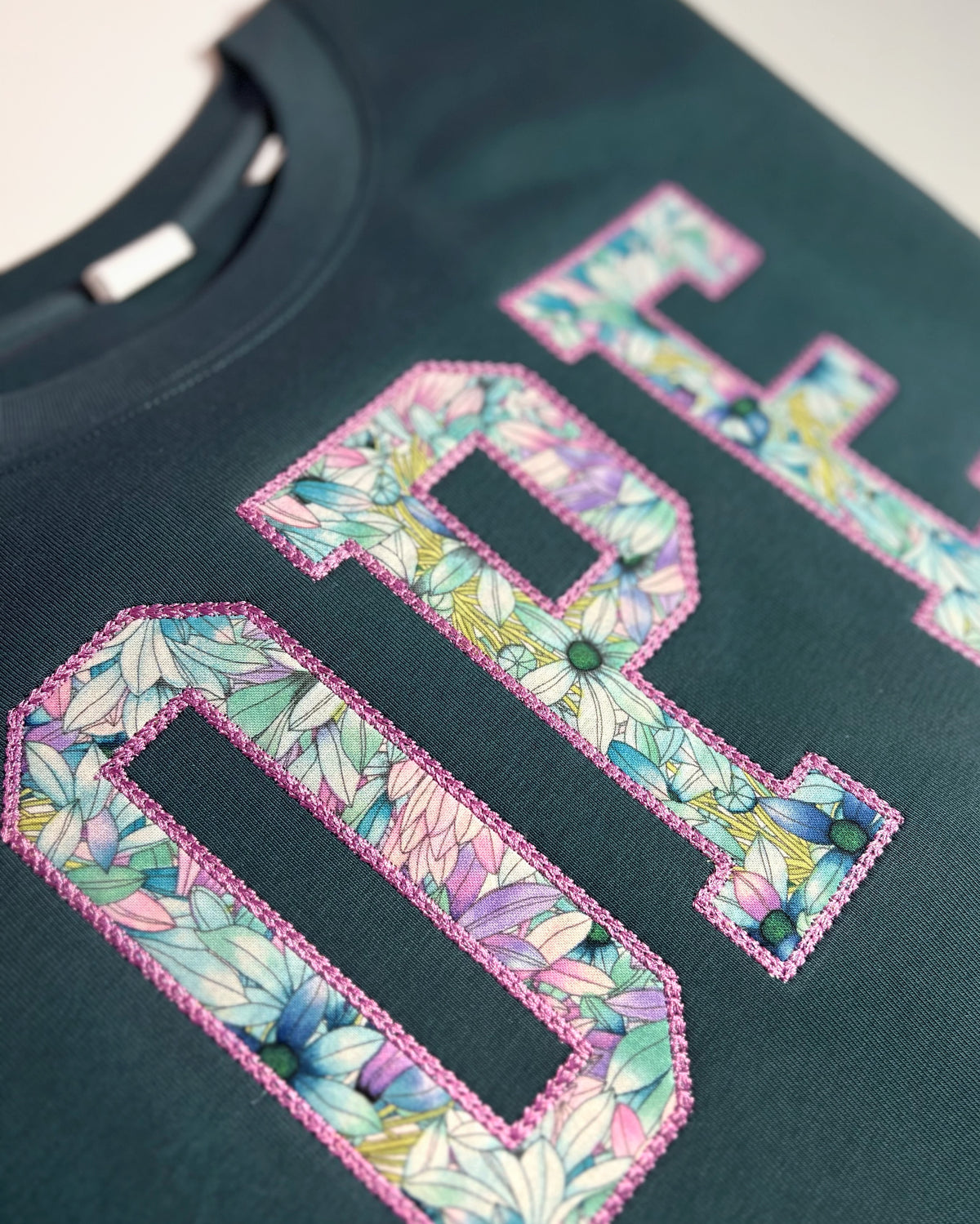 Close-up of floral fabric inside OPE appliqué on teal