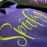 Purple and black garments with bright Spooky script embroidery