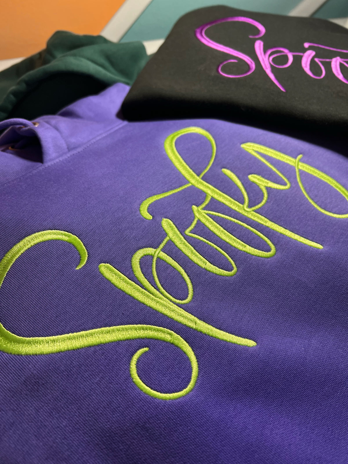 Purple and black garments with bright Spooky script embroidery