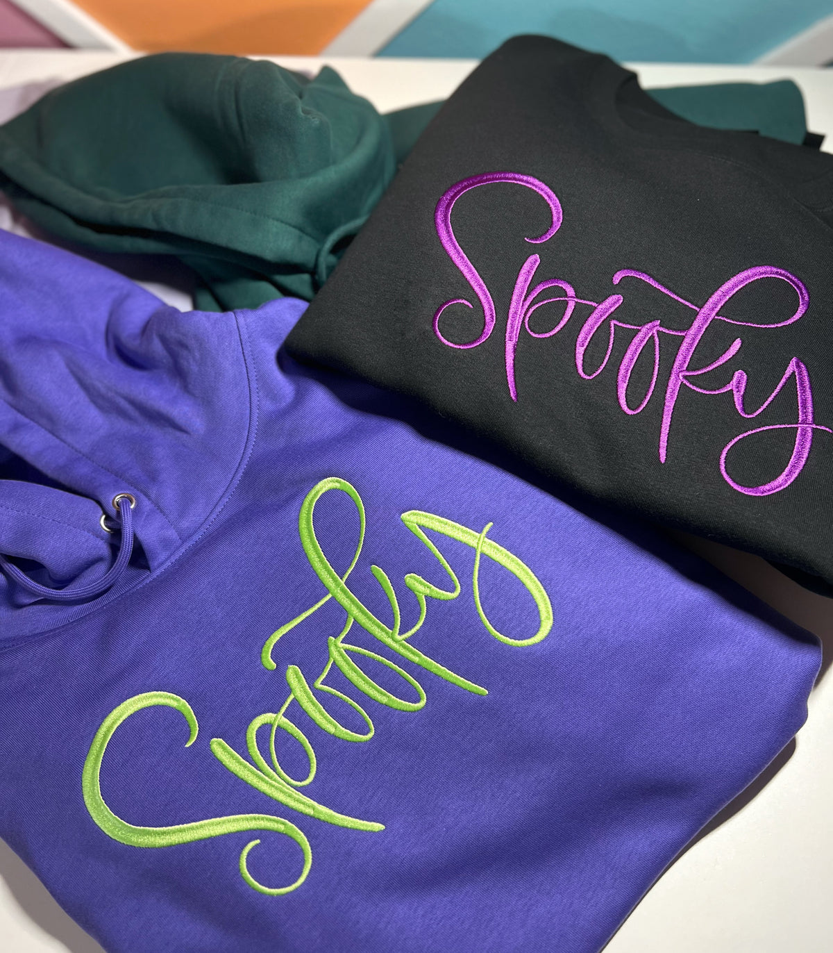 Purple Spooky hoodie beside black Spooky shirt