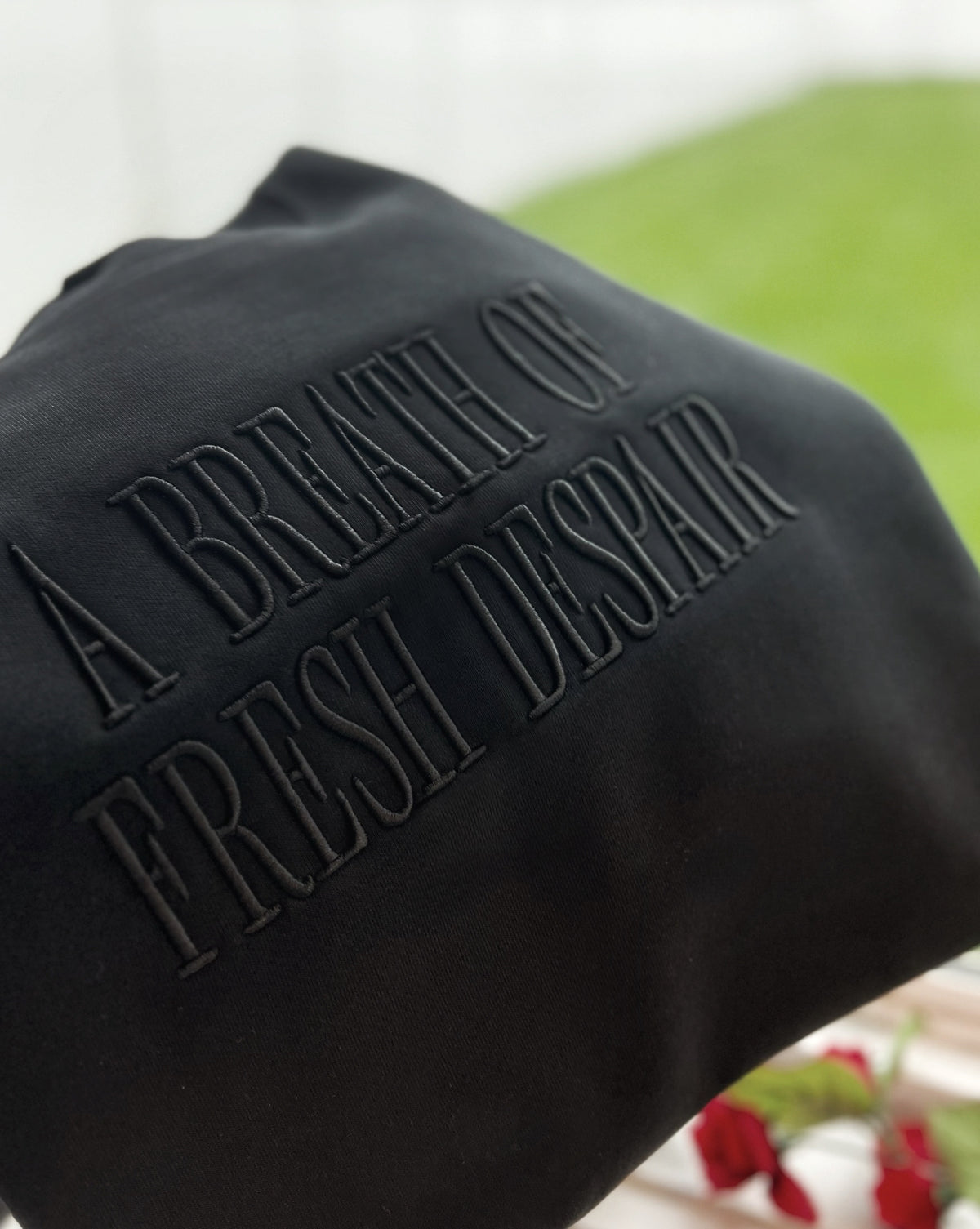Black embroidered Breath of Fresh Despair sweatshirt on hanger