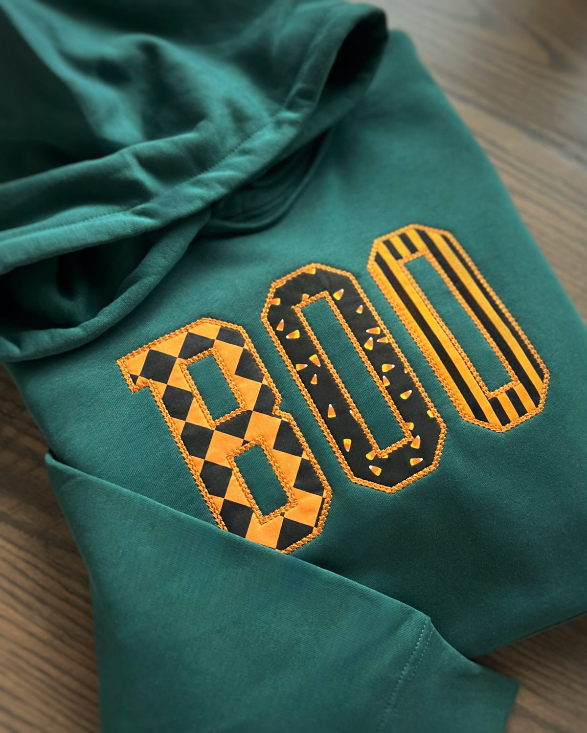 Green hoodie with orange-and-black patterned BOO appliqué