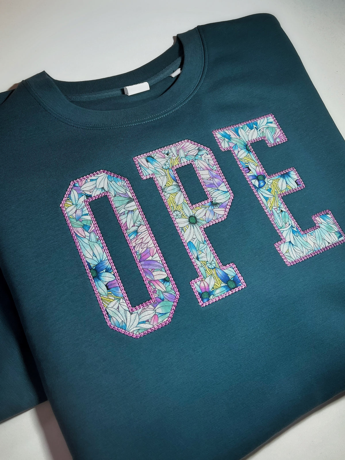 Teal sweatshirt with floral OPE appliqué