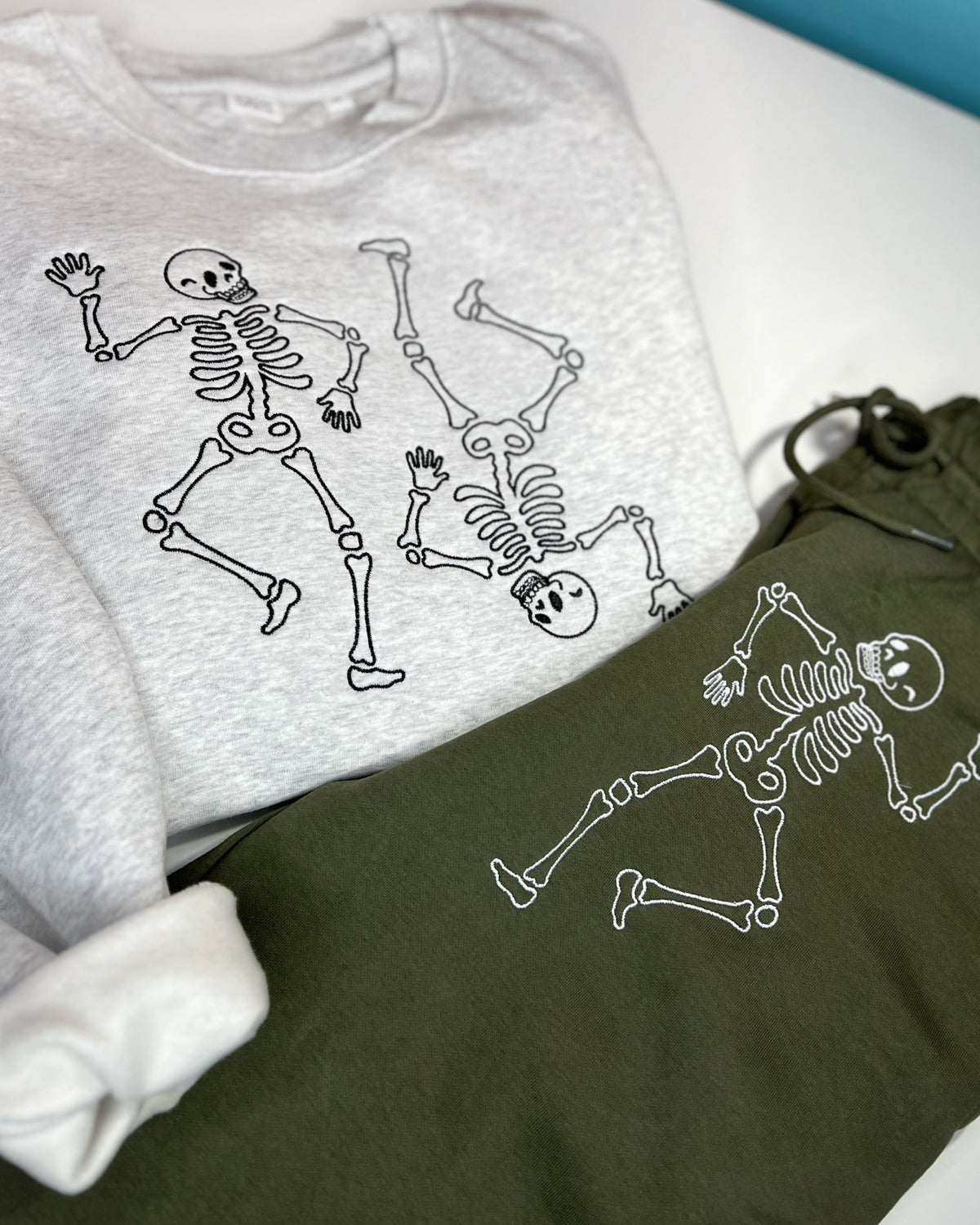 Gray sweatshirt with two dancing skeletons embroidered in dark thread