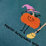 Teal sweatshirt with orange pumpkin in a witch hat and Happiest During Manic Episode lettering