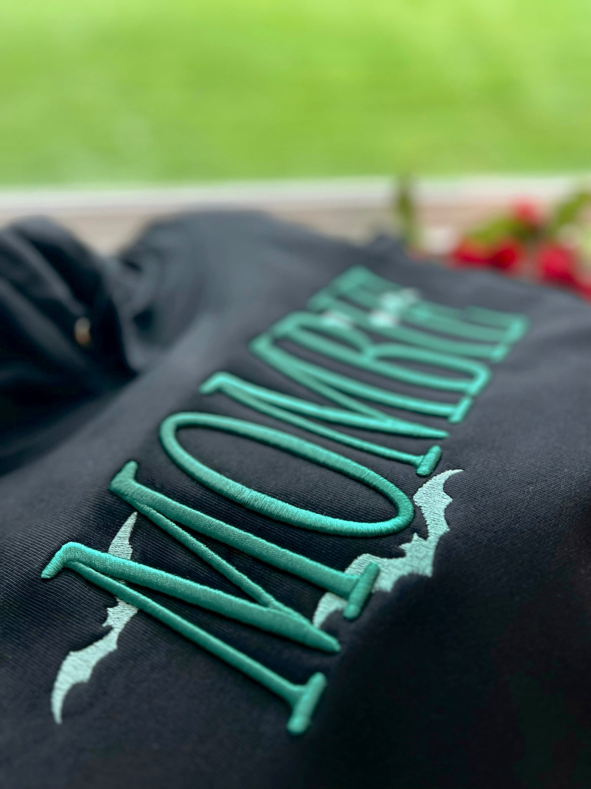Close-up of raised green MOMBIE lettering on black fabric