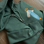 Green zip-up hoodie with embroidered pumpkin-headed scarecrow