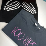 Black skeleton-hands sweatshirt beside gray BOO-BIES shirt