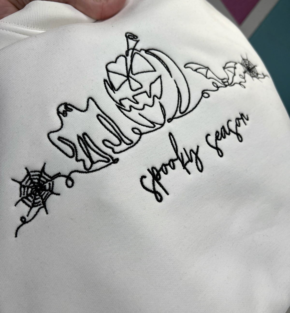 Close-up of embroidered ghost, pumpkin, bats, and spiderwebs