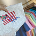 Gray garment with embroidered floral flag and Home script