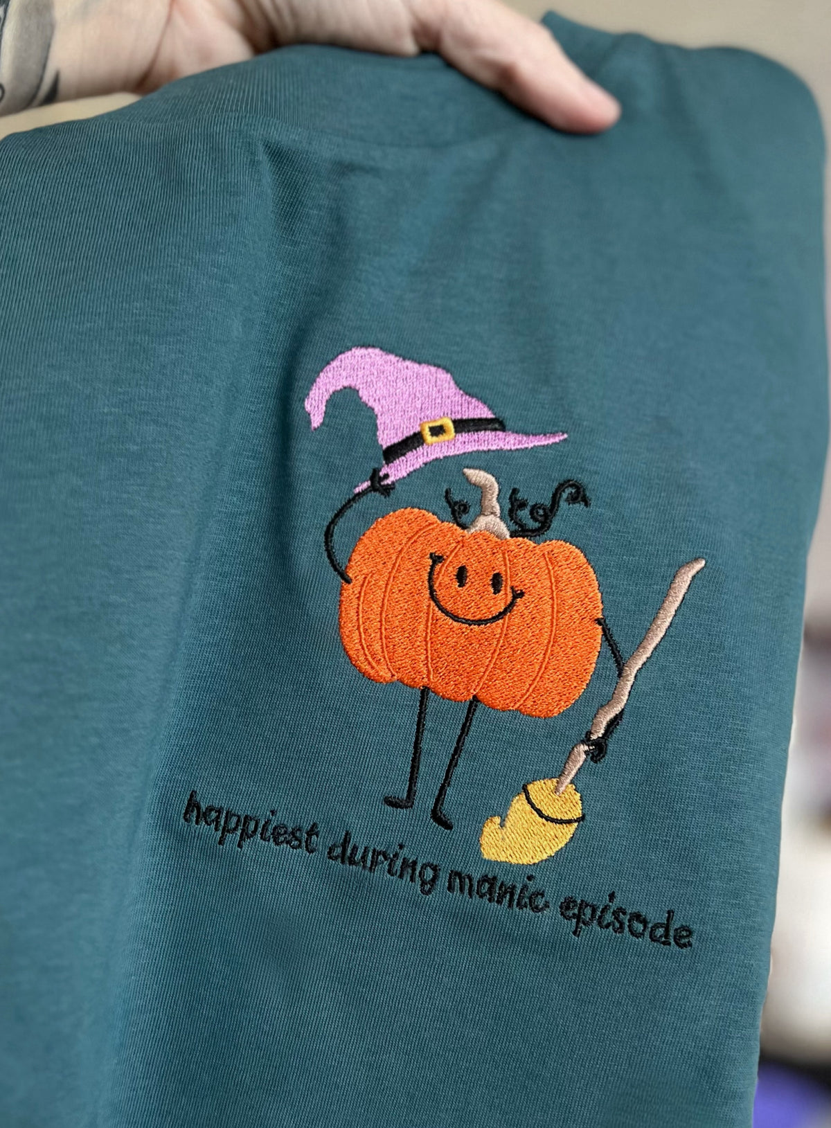 Close-up of pumpkin with broom and embroidered caption