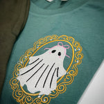 Close-up of framed ghost embroidery on green fabric