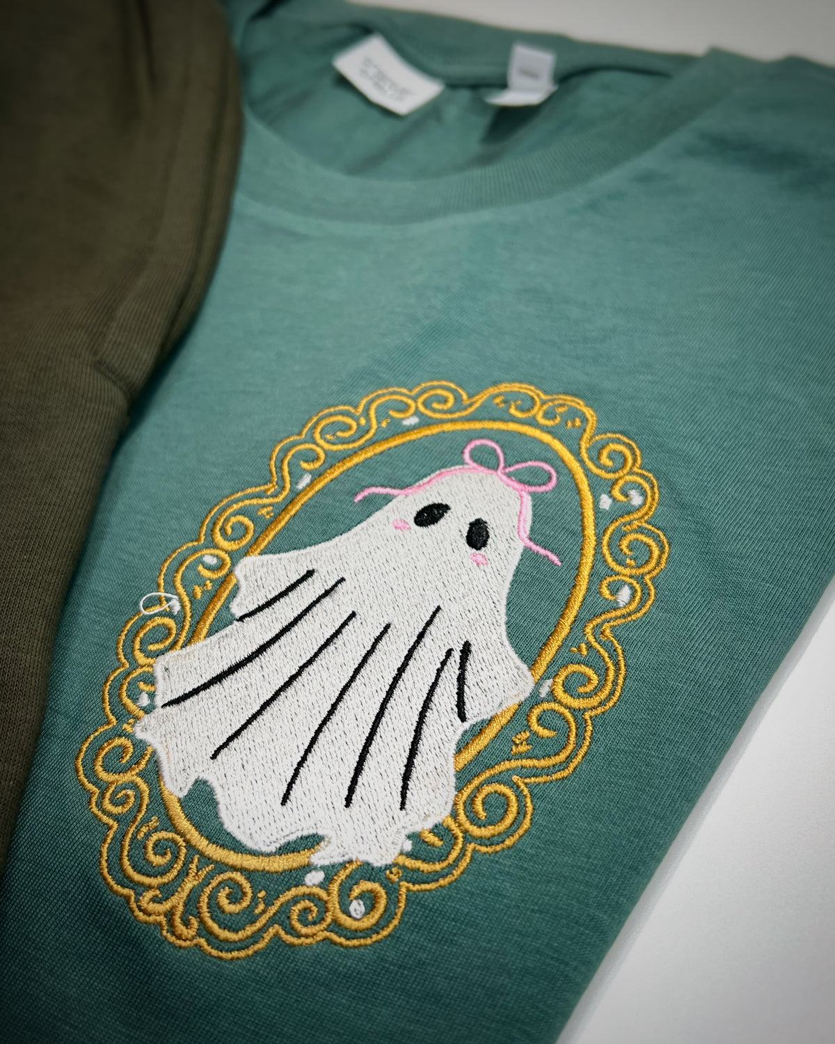 Close-up of framed ghost embroidery on green fabric
