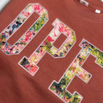 Close-up of floral OPE appliqué on terracotta fabric