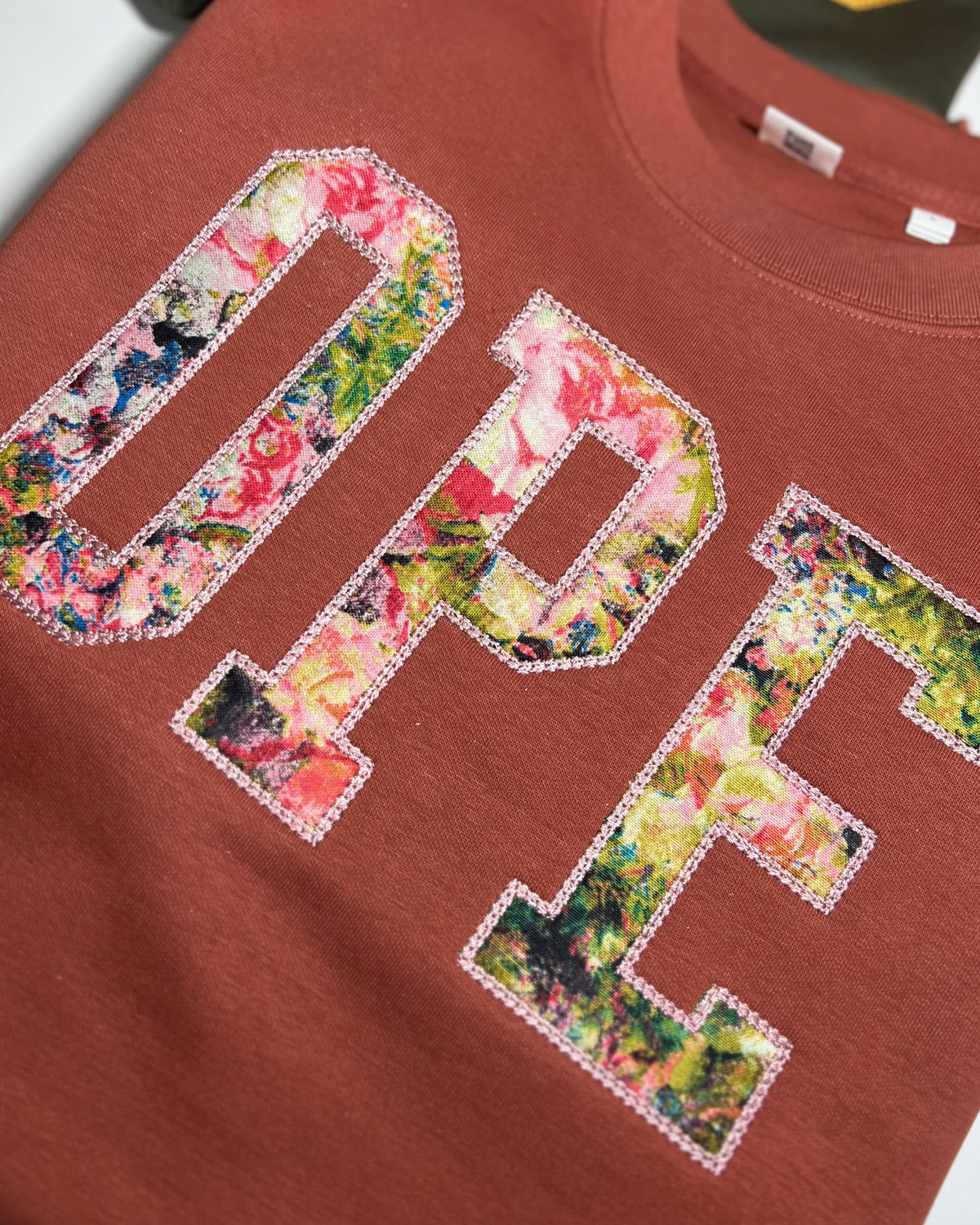 Close-up of floral OPE appliqué on terracotta fabric